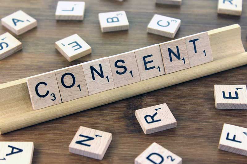 Le mot "CONSENT" est assemblé avec des lettres en bois, évoquant le consentement dans le traitement des données personnelles.