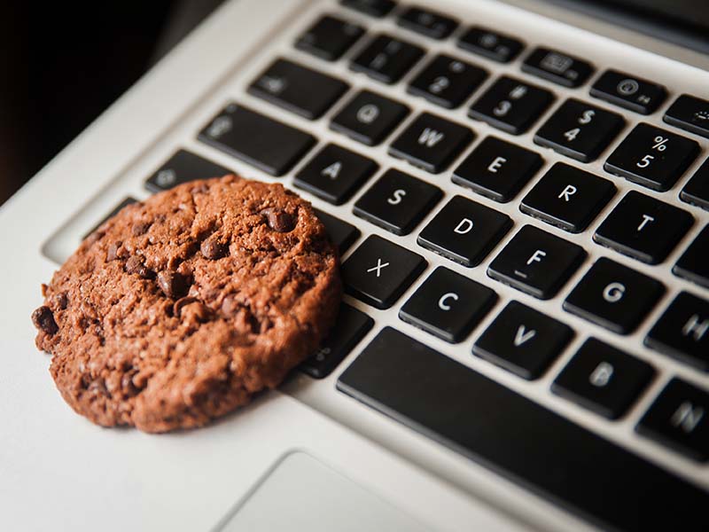 Un cookie au chocolat repose sur le clavier d'un ordinateur portable, métaphore visuelle pour les cookies internet et la gestion de la vie privée en ligne.