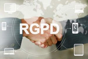 Deux personnes se serrent la main devant une interface graphique avec le sigle "RGPD" et des icônes de dispositifs connectés, soulignant l'accord sur la conformité au Règlement Général sur la Protection des Données.